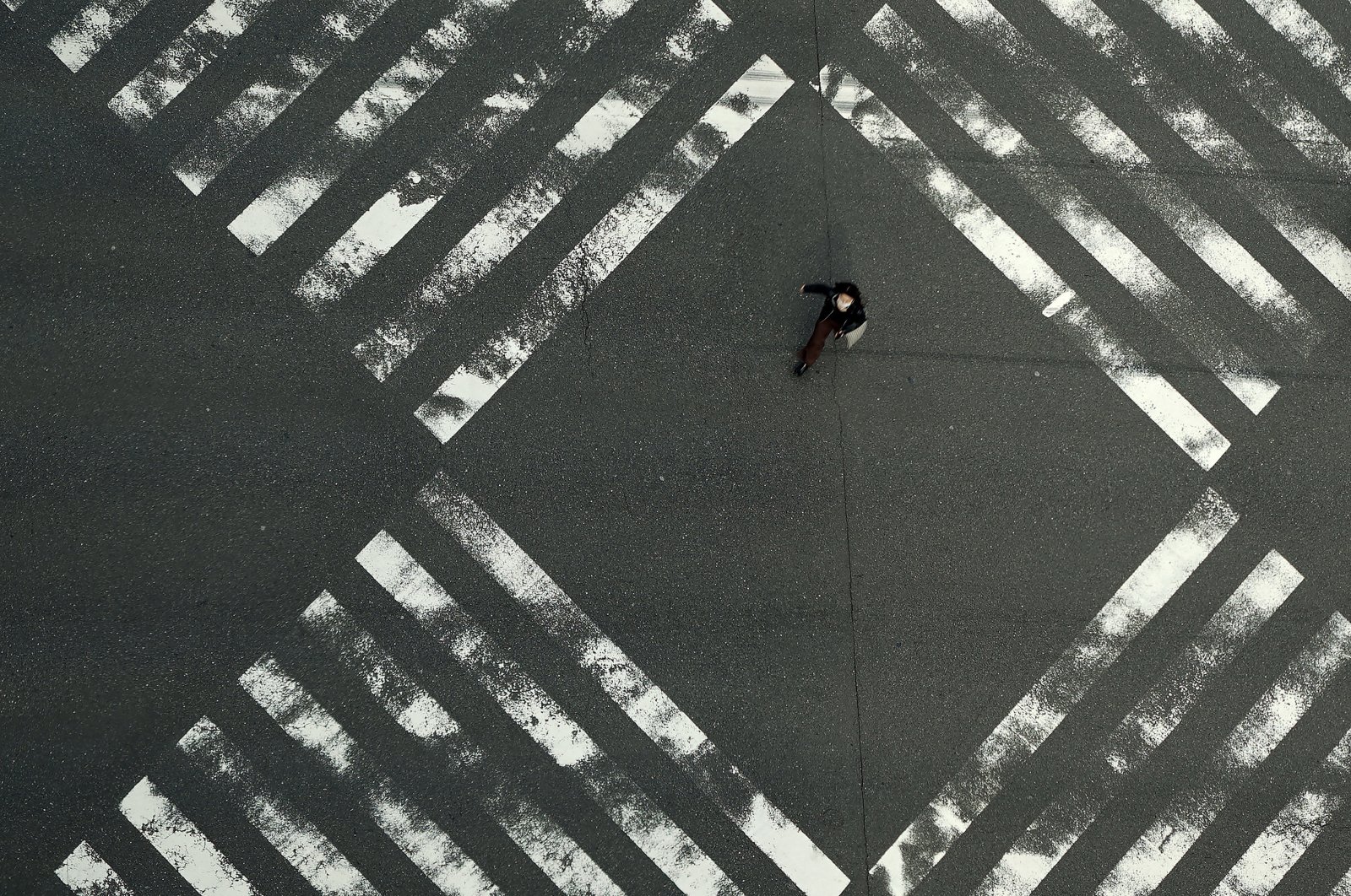 A woman walks through an empty pedestrian crossing in the Ginza shopping district in Tokyo, Friday, April 3, 2020. (AP Photo)