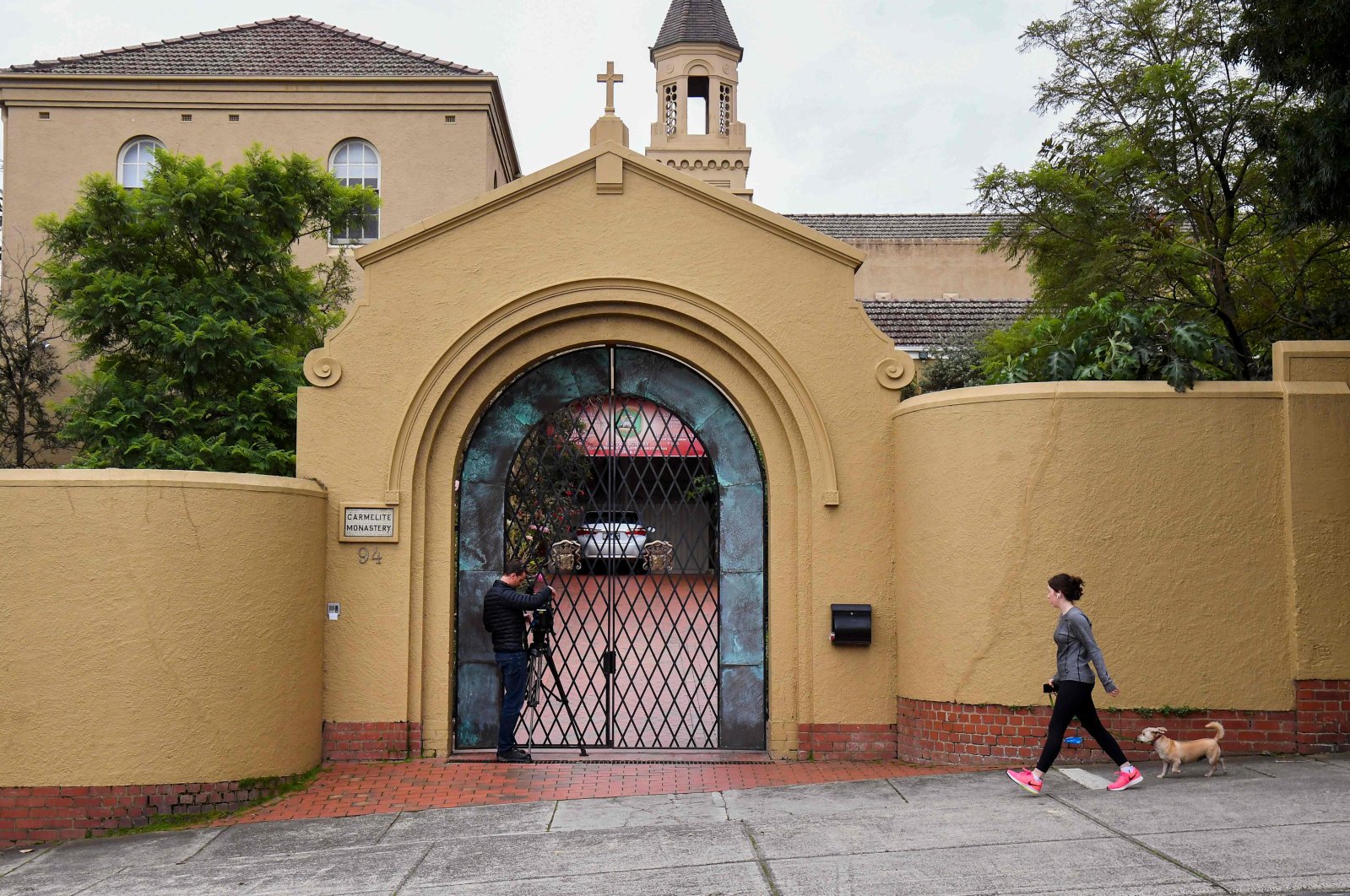 A woman walks her dog past the Carmelite Monastery in Melbourne, Australia, Tuesday, April 7, 2020, where Cardinal George Pell is staying after having been released from Barwon Prison earlier in the day. (AFP Photo)