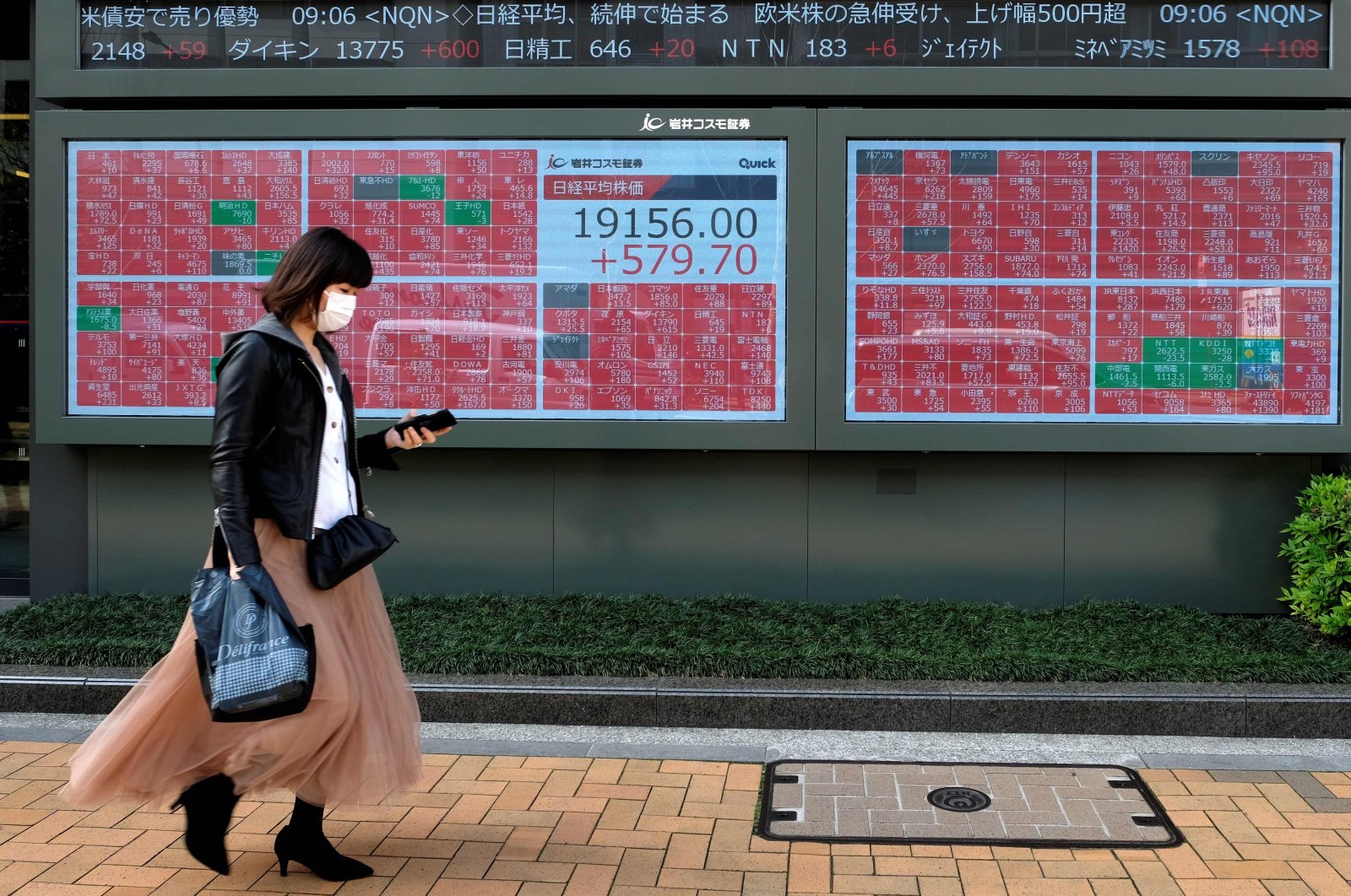 A pedestrian walks past a quotation board displaying share prices of the Tokyo Stock Exchange in Tokyo on April 7, 2020. (AFP Photo)
