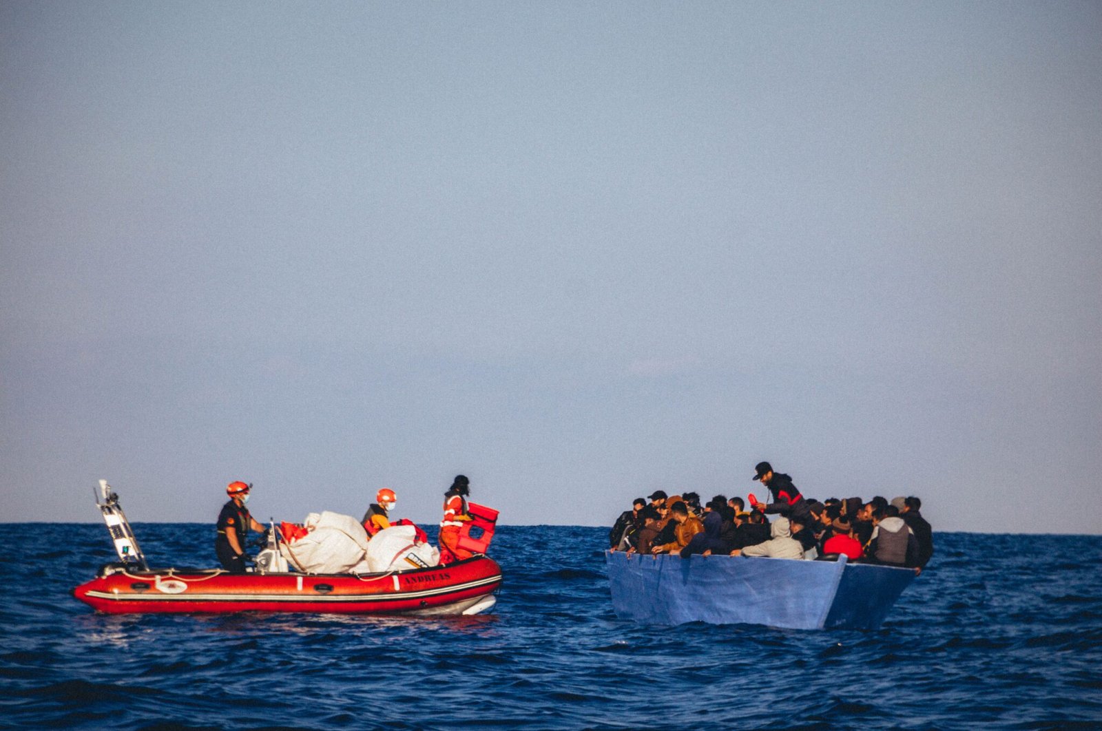 Members of Sea Eye on a rubber boat rescue people from a small wooden boat in distress off the Libyan coast, Monday, April 6, 2020. (AFP Photo)