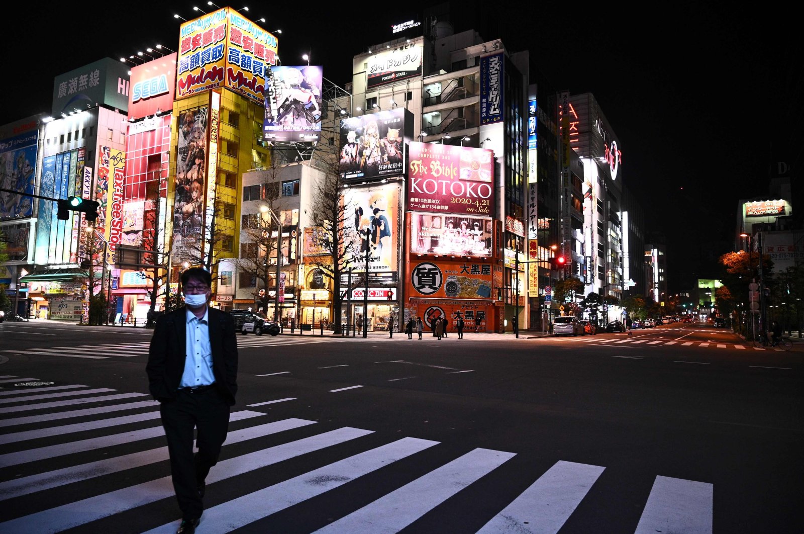 A man wearing a face mask walks across the road in the Akihabara district of Tokyo, Tuesday, April 7, 2020. (AFP Photo)