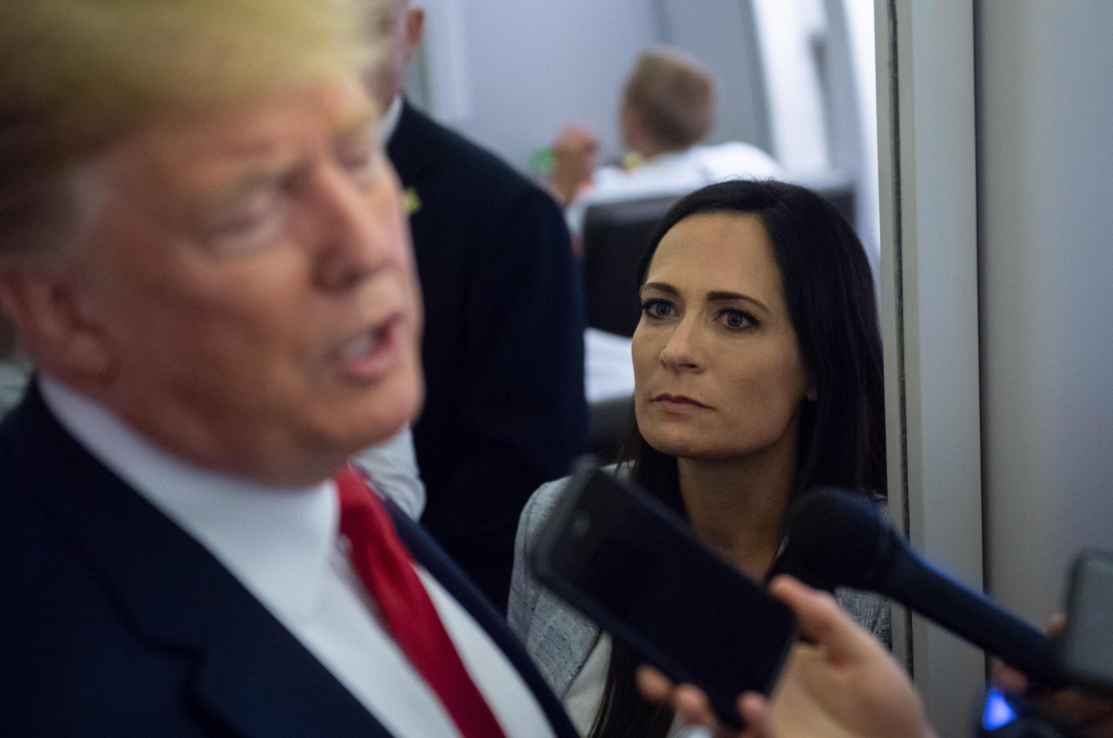 Former White House press secretary Stephanie Grisham listens as U.S. President Donald Trump speaks to the media aboard Air Force One while flying between El Paso, Texas and Joint Base Andrews in Maryland, Aug. 7, 2019. (AFP Photo)