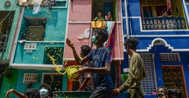 Volunteers throw a mixture of water, neem herb and turmeric – which they tout as a natural disinfectant – on a street in a residential area during a government-imposed nationwide lockdown prompted by the coronavirus pandemic, Chennai, Tuesday, April 7, 2020. (AFP Photo)