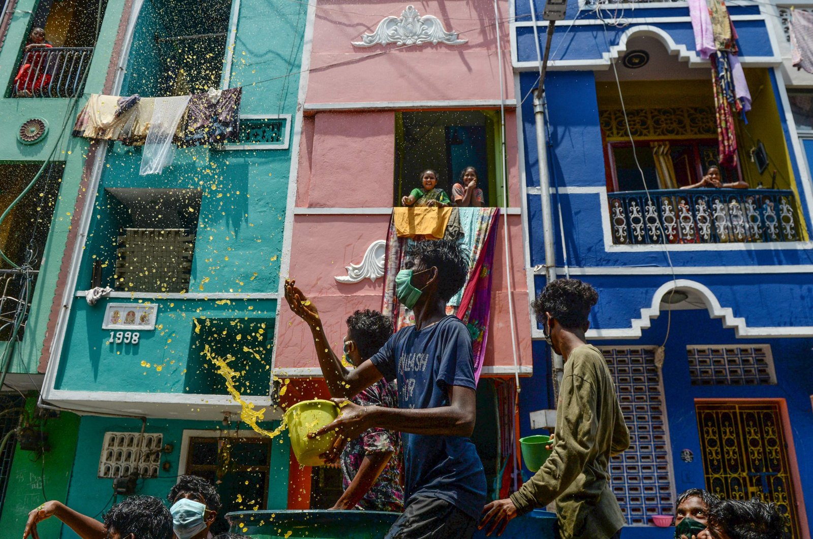 Volunteers throw a mixture of water, neem herb and turmeric – which they tout as a natural disinfectant – on a street in a residential area during a government-imposed nationwide lockdown prompted by the coronavirus pandemic, Chennai, Tuesday, April 7, 2020. (AFP Photo)