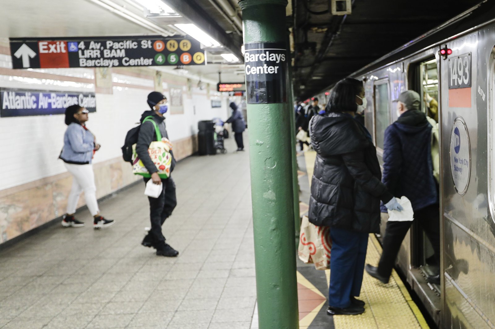 Patrons, wearing masks, board a train at the Atlantic Avenue station in the Brooklyn borough of New York, Tuesday, April 7, 2020. (AP Photo)