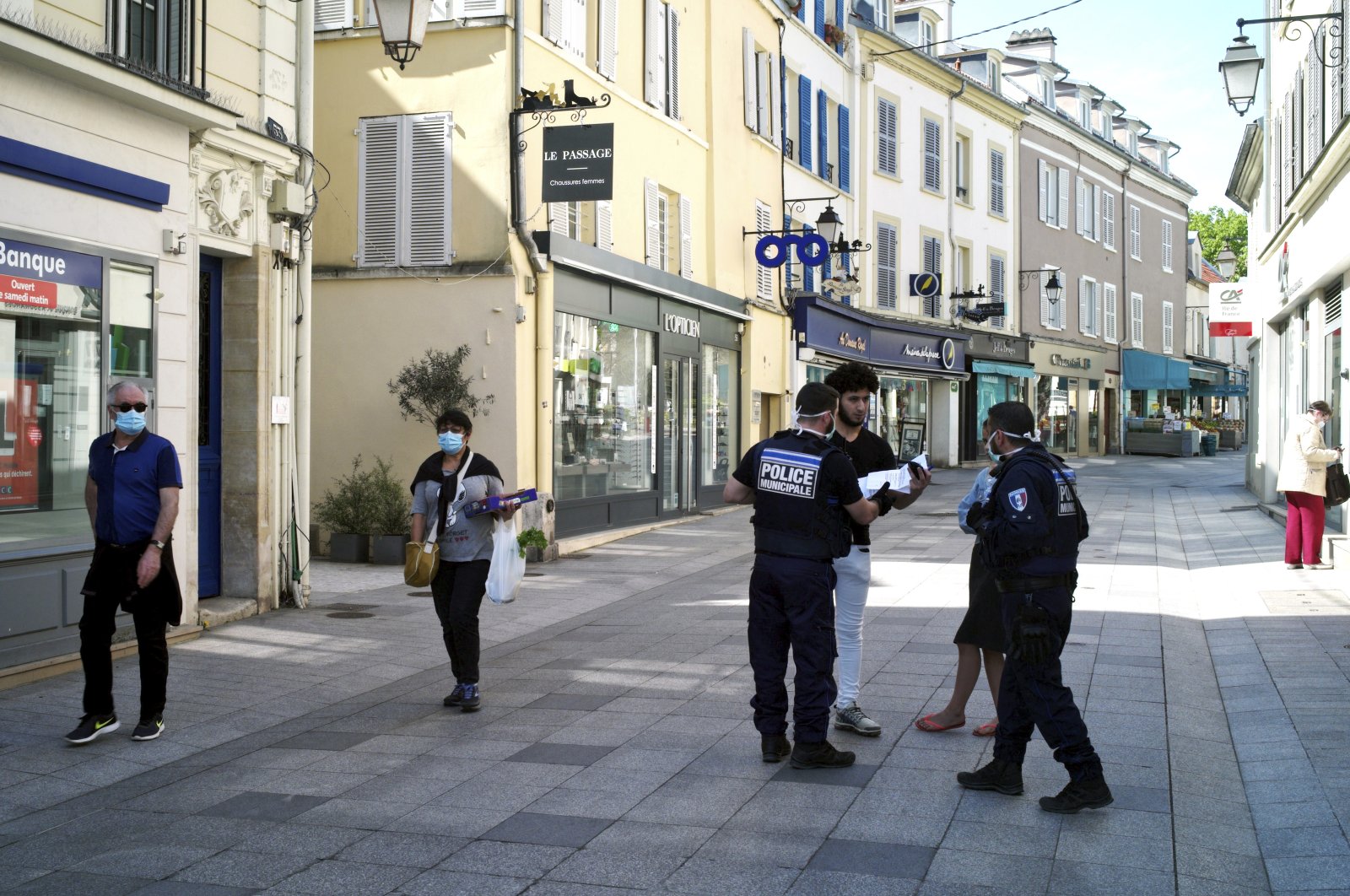 Municipal police officers check documents as they patrol in a street of Sceaux during nationwide confinement measures to counter the COVID-19, in Sceaux, south of Paris, Wednesday, April 8, 2020 (AP Photo)