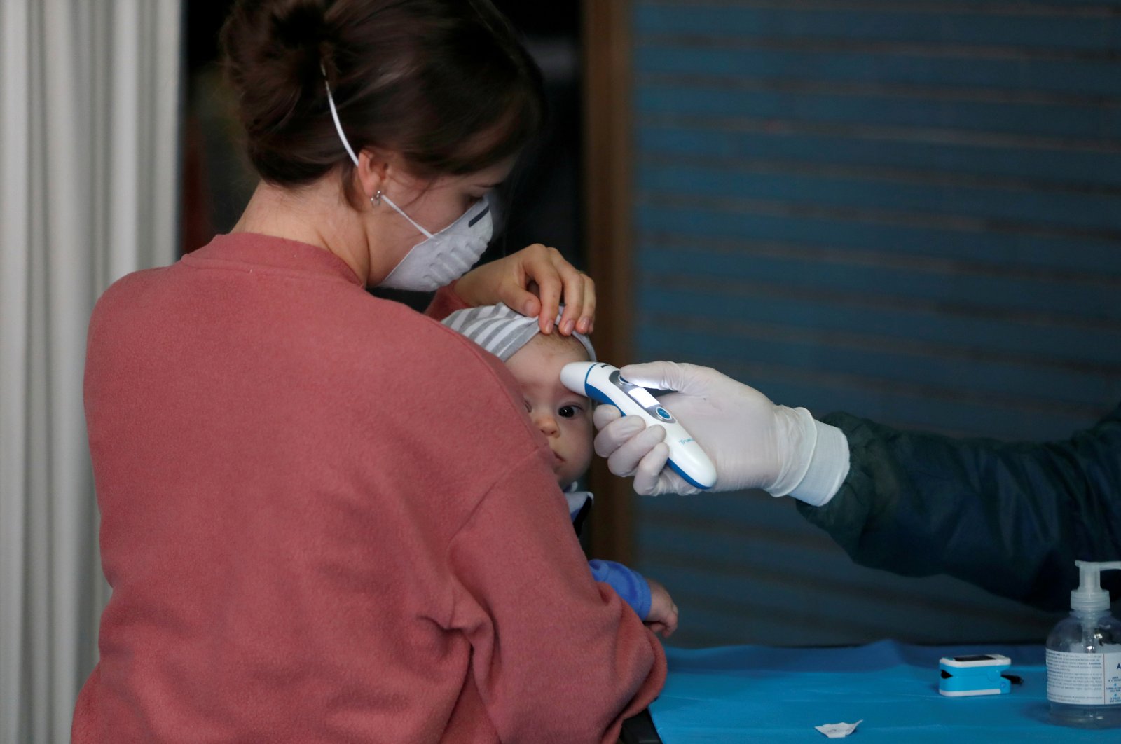A doctor checks a temperature of a baby during medical tests by nongovernmental organization Intersos in a squatted building, Rome, April 3, 2020. (REUTERS Photo)