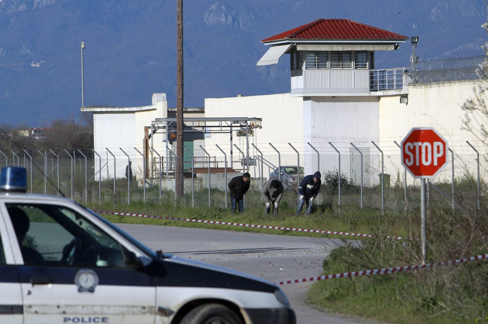 Police officers search for evidence in front of a prison near the city of Trikala, central Greece, March 23, 2013. (AP Photo)