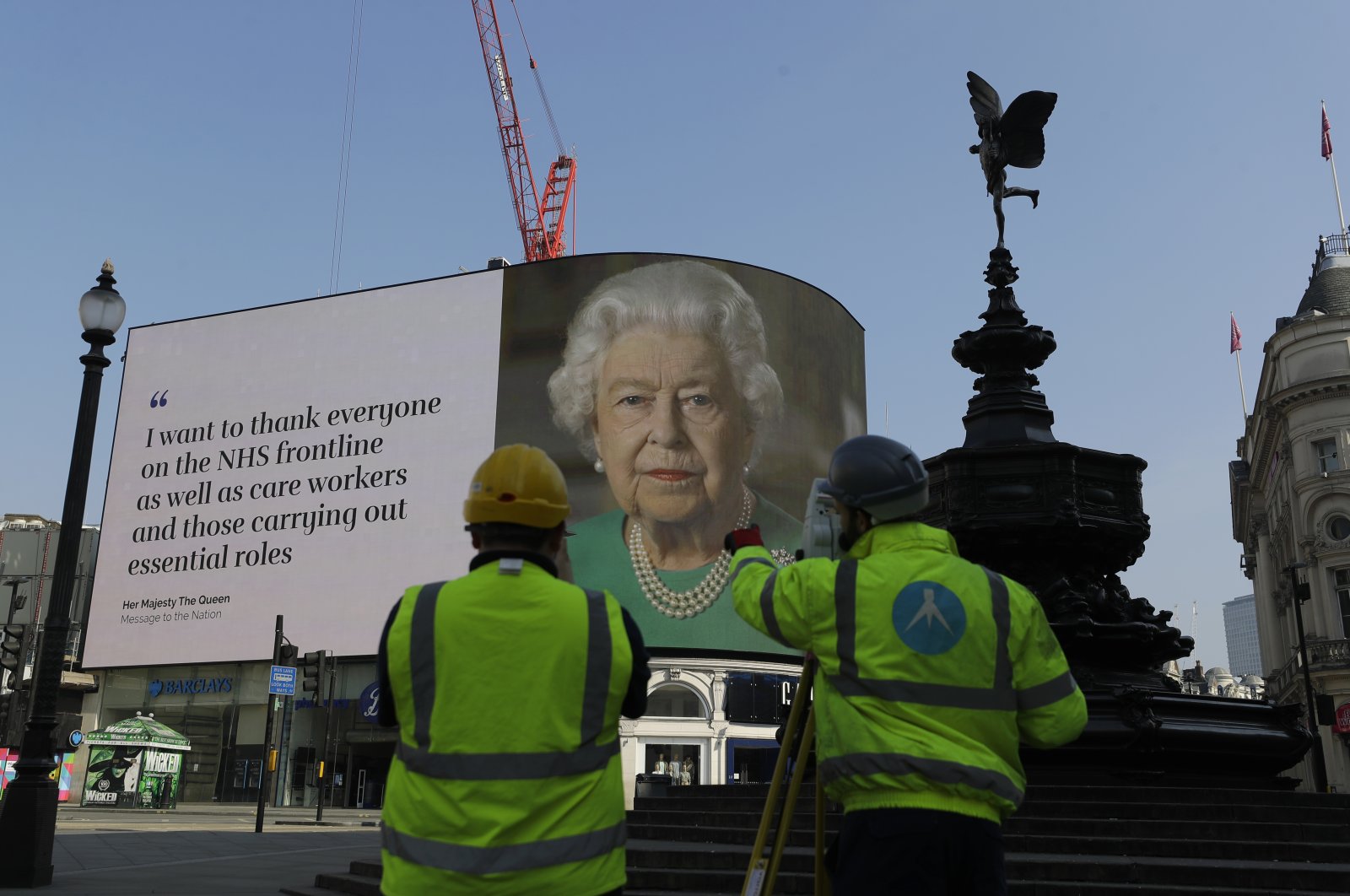 An image of Britain's Queen Elizabeth II and quotes from her historic television broadcast commenting on the coronavirus pandemic are displayed on a big screen behind the Eros statue at Piccadilly Circus in London, April 9, 2020. (AP Photo)