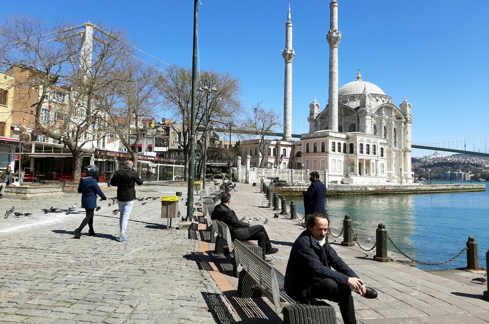 People sit on the benches in Ortaköy, Istanbul, Turkey, April 9, 2020. (Photo by Mustafa Kaya)