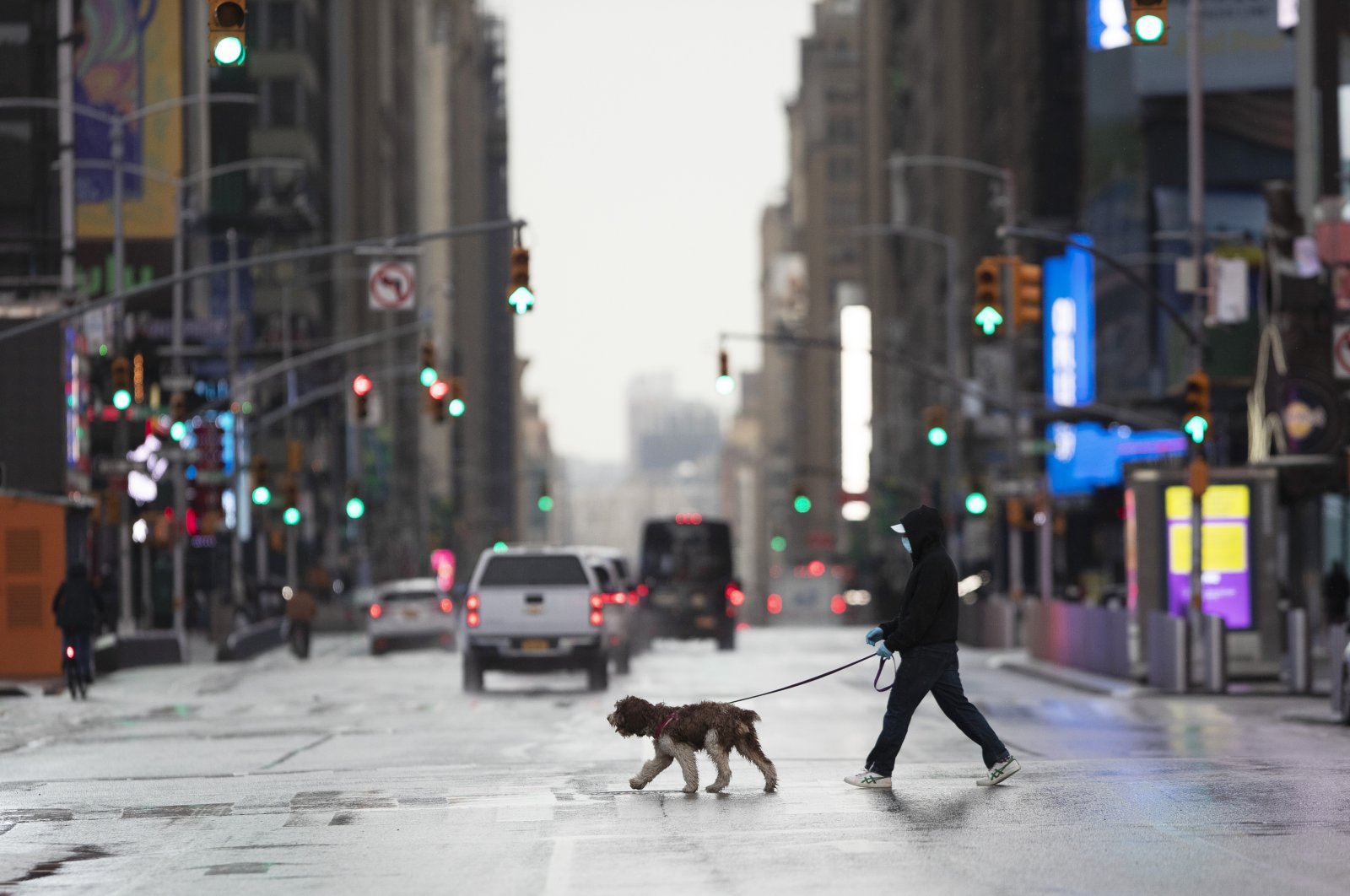 A man wearing a mask walks his dog through a quiet Times Square during the coronavirus epidemic in New York, April 9, 2020. (AP Photo)