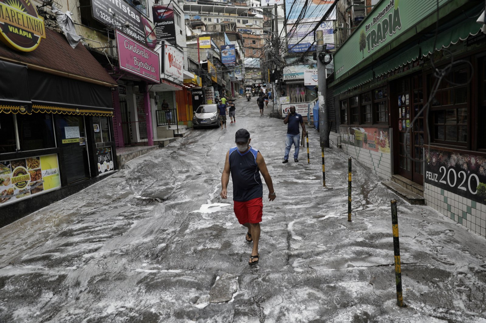 A man wearing a protective mask walks on a street disinfected by cleaners during the  COVID-19 outbreak, at the Rocinha slum in Rio de Janeiro, Brazil April 10, 2020. (REUTERS Photo)
