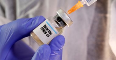 A woman holds a small bottle labelled with a "Vaccine COVID-19" sticker and a medical syringe in this illustration taken April 10, 2020. (REUTERS Photo)