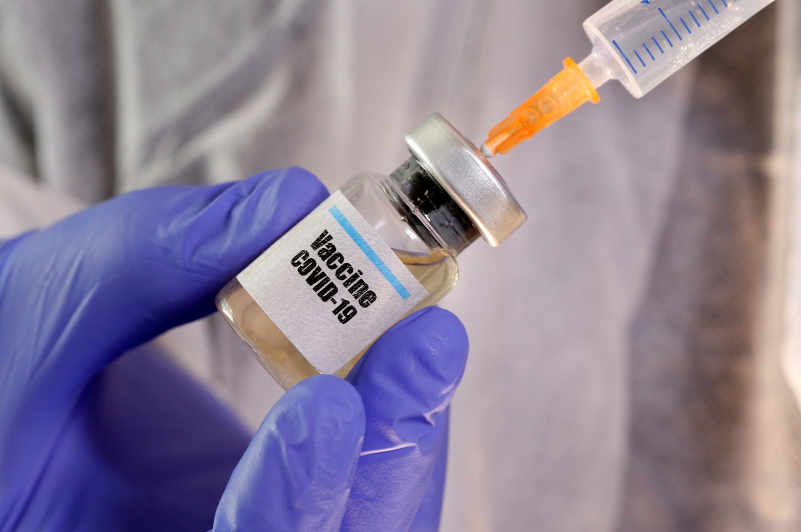 A woman holds a small bottle labelled with a "Vaccine COVID-19" sticker and a medical syringe in this illustration taken April 10, 2020. (REUTERS Photo)