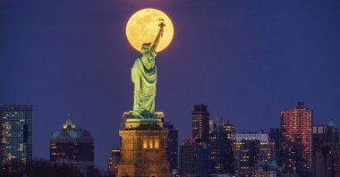The full moon rises behind the Statue of Liberty in New York, March 9, 2020. (AP Photo)