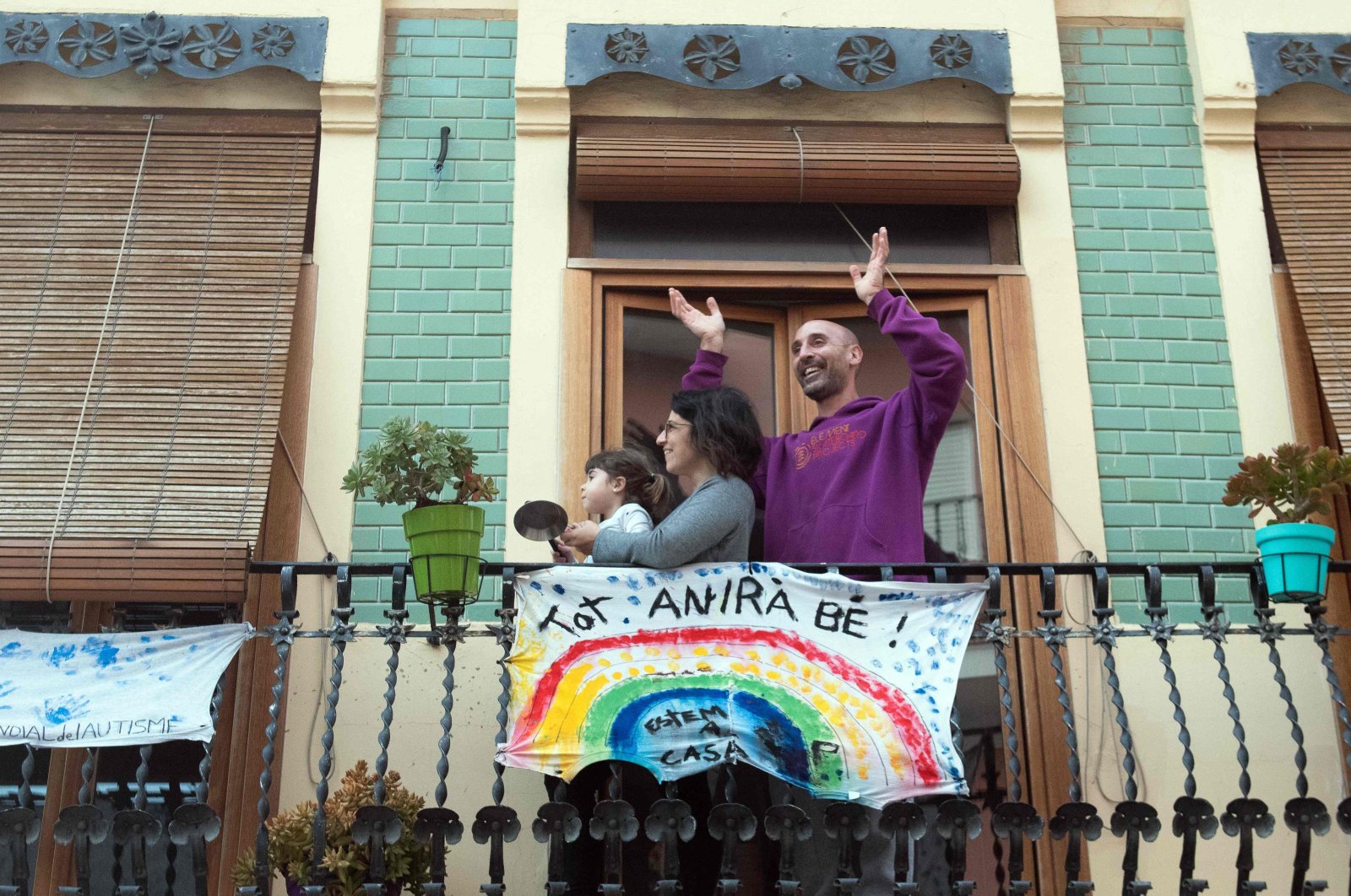 A family applauds from their balcony, adorned with a banner reading "Everything will be ok," in El Cabanal, Valencia, April 9, 2020. (AFP Photo)