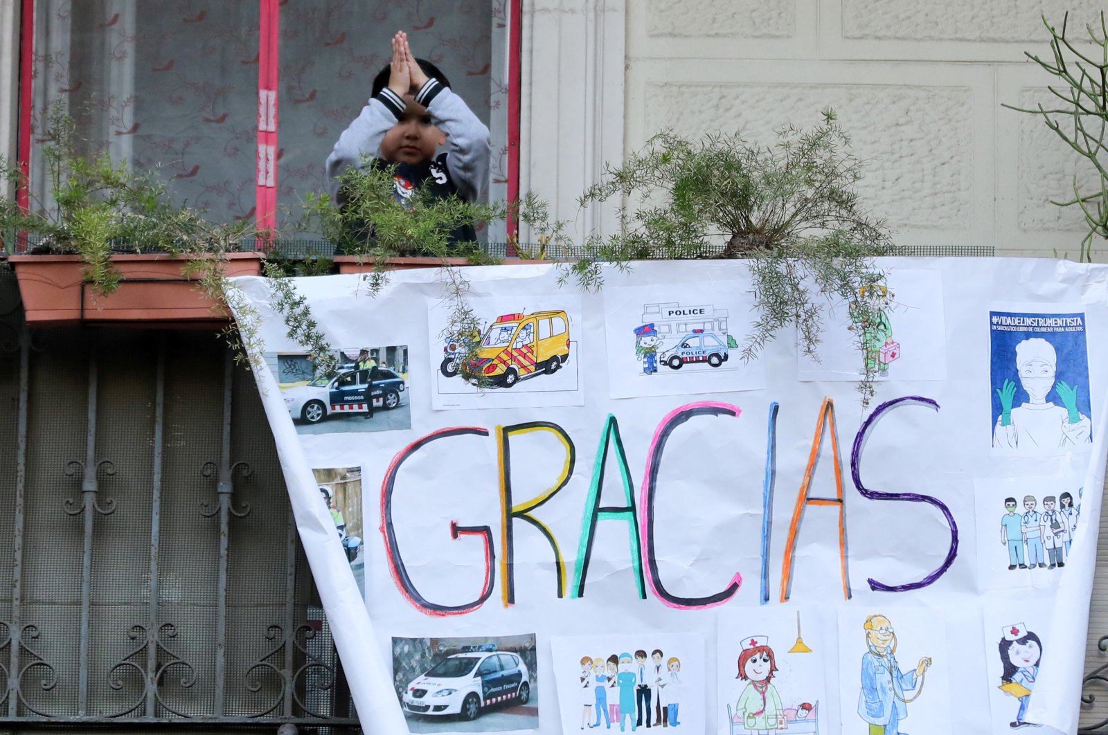 A child gestures from the balcony of his house in support of healthcare workers, in front of the Dos de Maig Hospital, Barcelona, Apr.11, 2020. (REUTERS Photo)