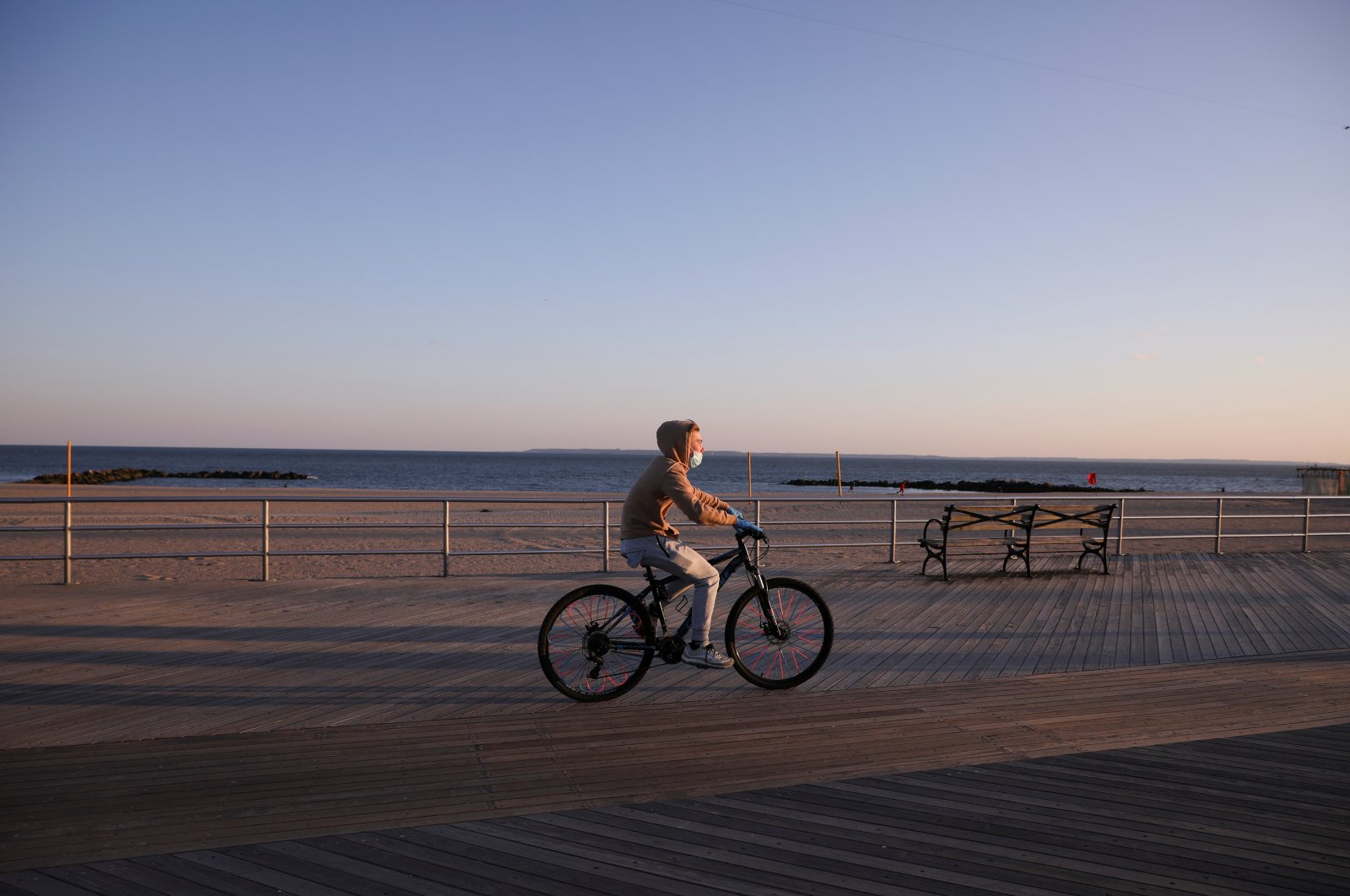 A bicyclist wears a mask and cycles along the mostly empty Coney Island boardwalk, Brooklyn, New York, U.S., April 11, 2020. (REUTERS Photo)