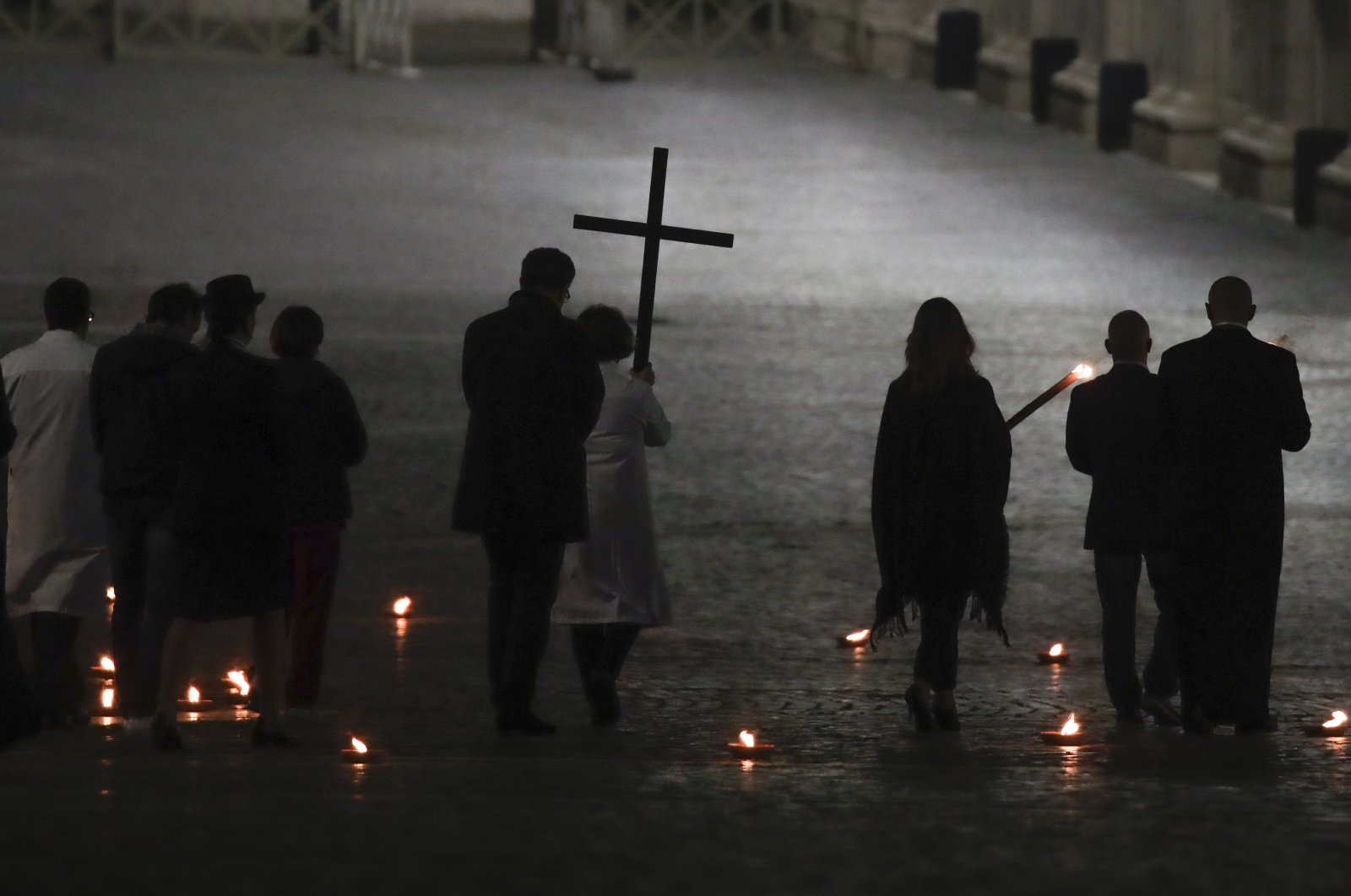A woman holds the cross during the Via Crucis – or Way of the Cross – ceremony in St. Peter's Square, empty of the faithful following Italy's ban on gatherings to contain the coronavirus contagion, at the Vatican, April 10, 2020. (AP Photo)