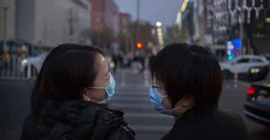 People wearing face masks to help curb the spread of the new coronavirus laugh as they cross an intersection in Beijing, Friday, April 10, 2020. (AP Photo)
