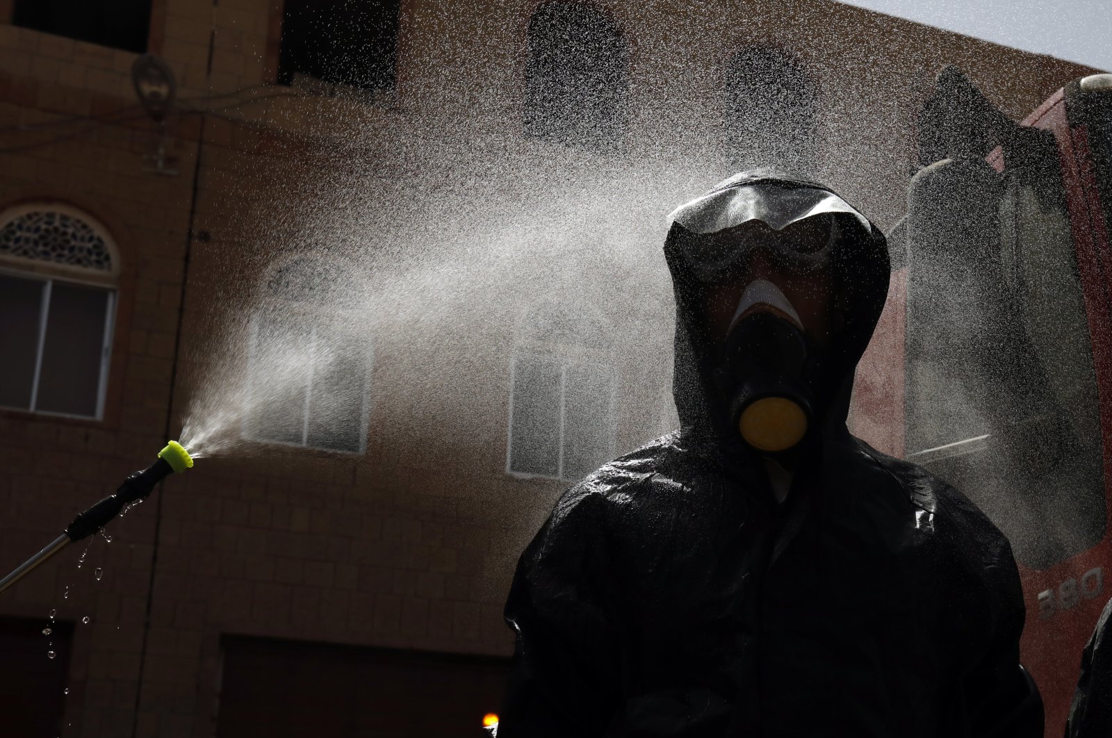 A staff of the Yemeni civil defense wearing protective gear, is decontaminated during a demonstration of an anti-proliferation training of the SARS-CoV-2 coronavirus, in Sanaa, Yemen, 12 April 2020. (EPA Photo)