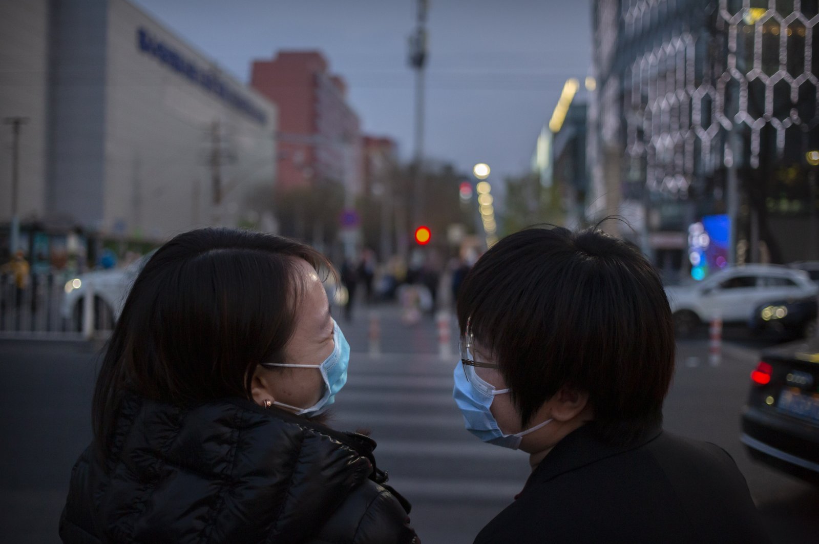 People wearing face masks to help curb the spread of the new coronavirus laugh as they cross an intersection in Beijing, Friday, April 10, 2020. (AP Photo)