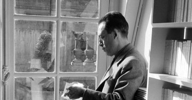 French writer Albert Camus reads outside his publishing firm's office, Paris, 1957.