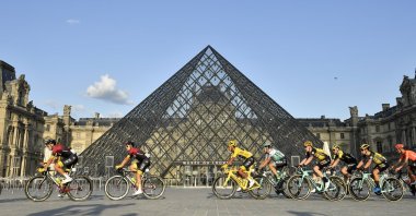 Colombia's Egan Bernal (C) wearing the overall leader's yellow jersey passes by the pyramid of the Louvre museum with the pack during the final stage of the Tour de France cycling race, Paris, France, July 28, 2019. (AP Photo)
