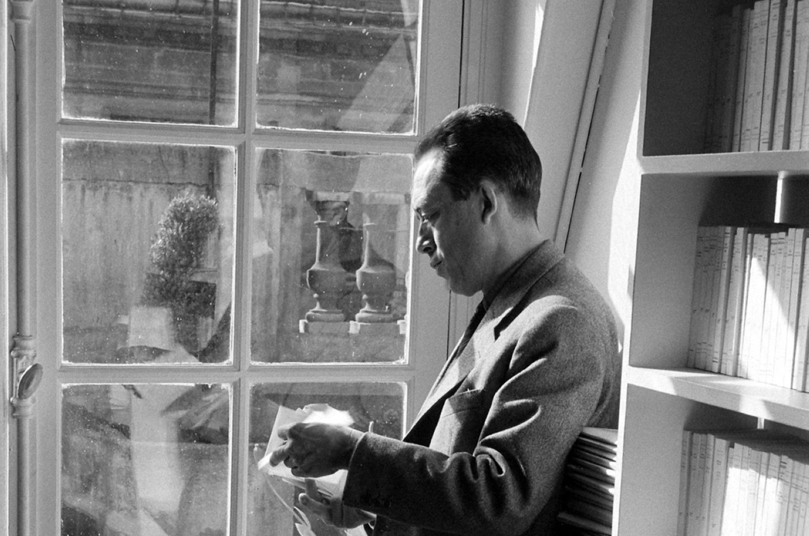 French writer Albert Camus reads outside his publishing firm's office, Paris, 1957.