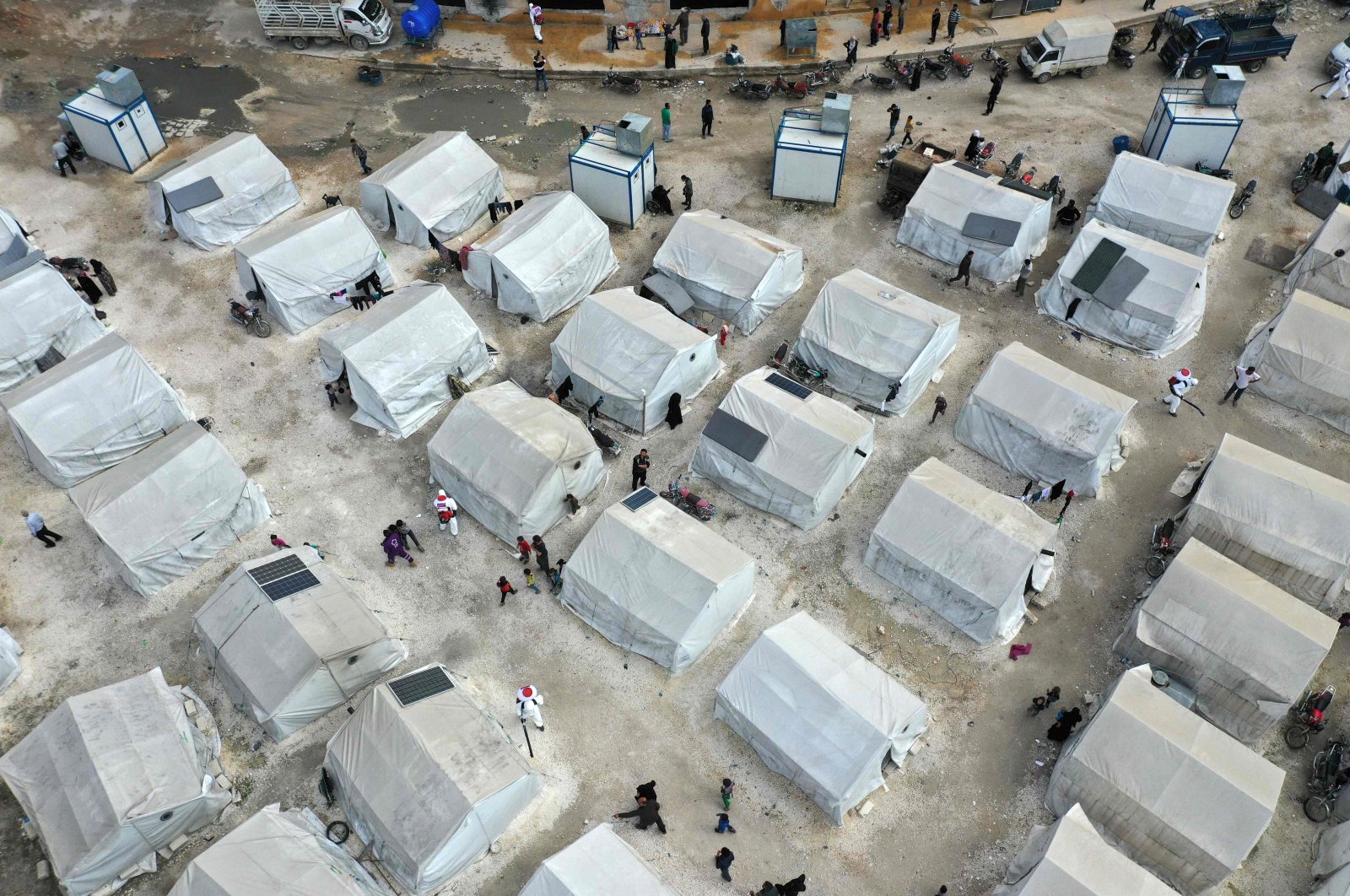 A drone image taken on April 9, 2020, shows sanitation workers disinfecting a camp for displaced Syrians next to the Idlib municipal stadium in the northwestern Syrian city, during a campaign to limit the spread of the coronavirus pandemic. (AFP Photo)