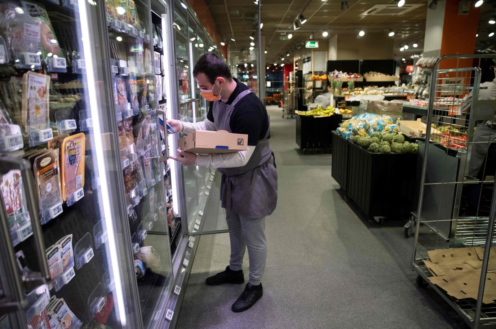 An employee wearing a protective mask stocks the cold shelves, before the opening of a Franprix supermarket, Paris, April 8, 2020. (AFP Photo)