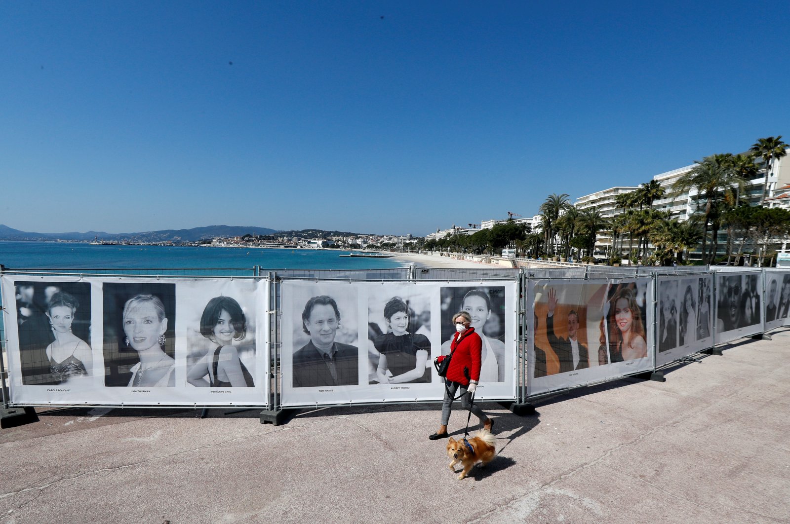 A woman walks past photos of the Cannes Film festival on the Croisette in Cannes as a lockdown is imposed to slow the rate of the coronavirus disease (COVID-19) in France, March 18, 2020. (Reuters Photo)
