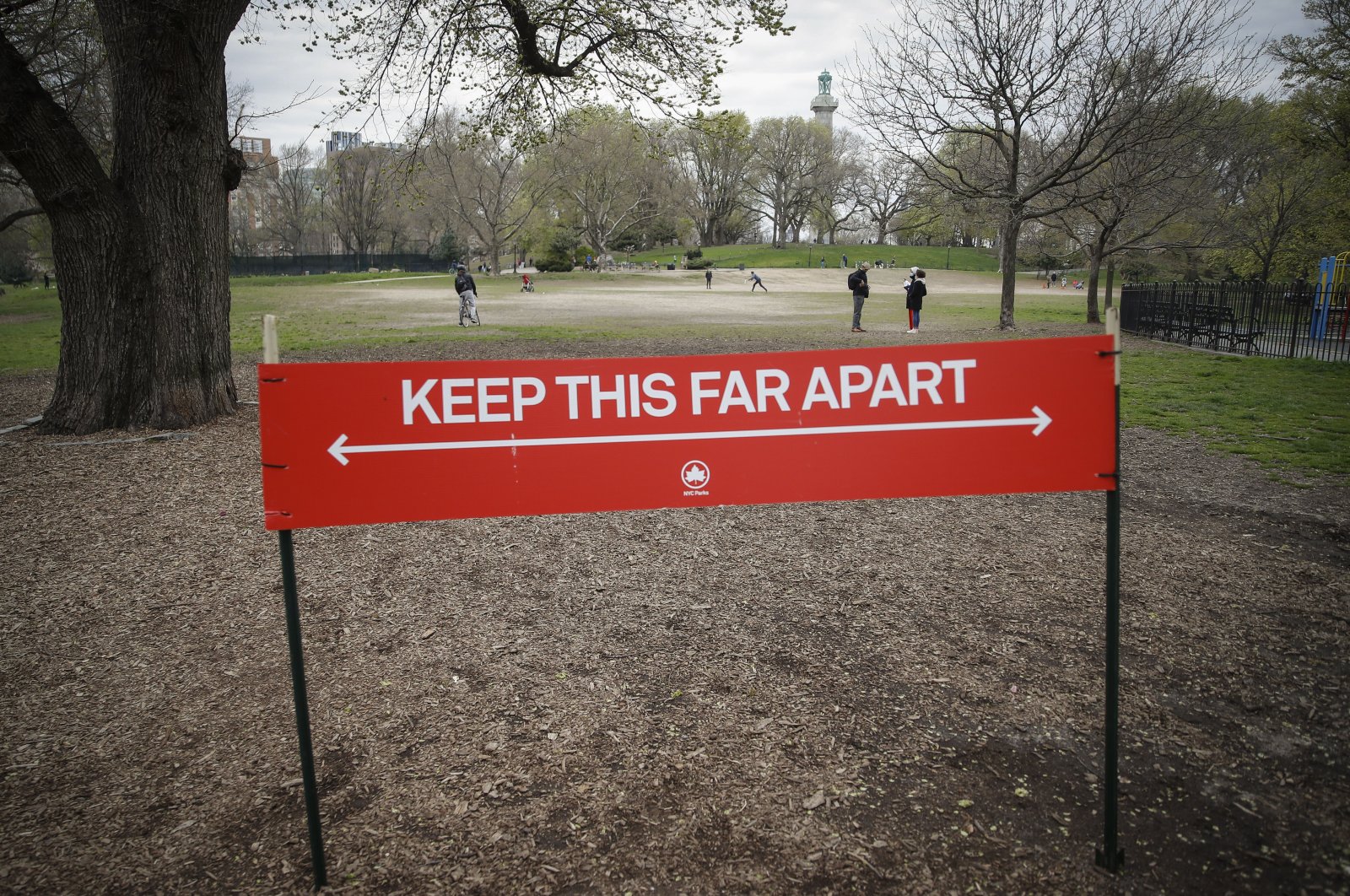 A sign by the New York City Department of Parks and Recreation indicates the appropriate measurement for social distancing as pedestrians linger in a field at Fort Greene Park in New York City, New York, U.S., April 14, 2020. (AP Photo)