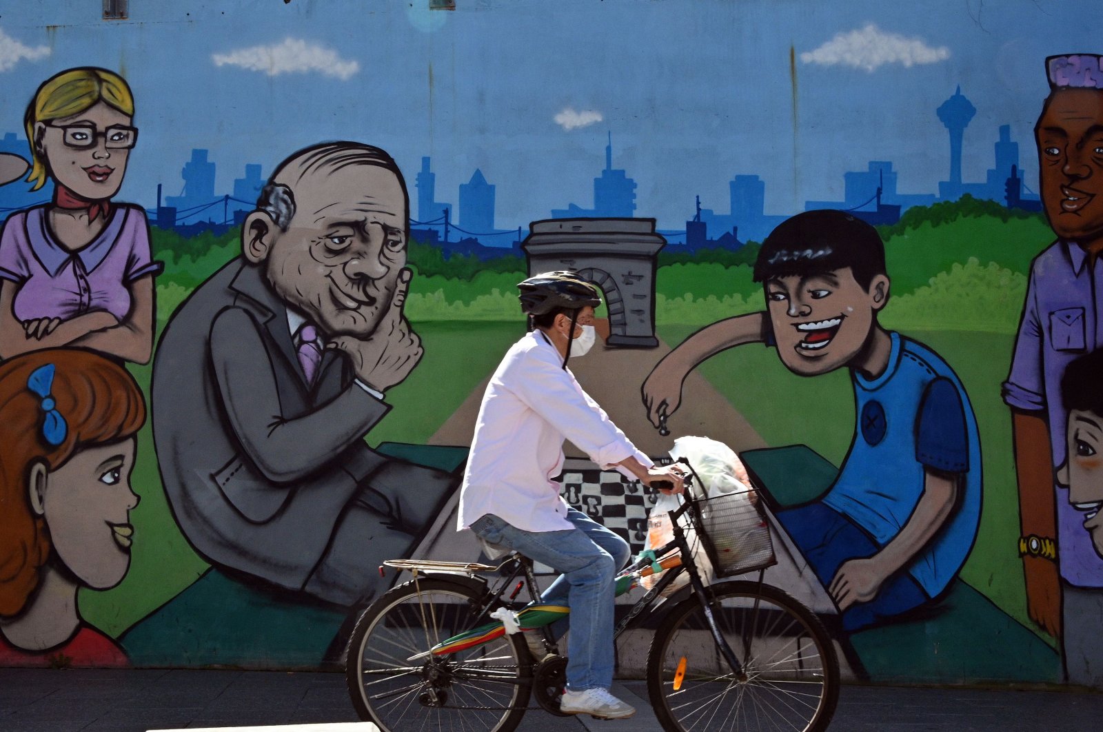 A man wearing a face mask bicycles past a mural in the Burwood suburb of Sydney on April 14, 2020, amid the COVID-19 coronavirus pandemic. (AFP Photo)