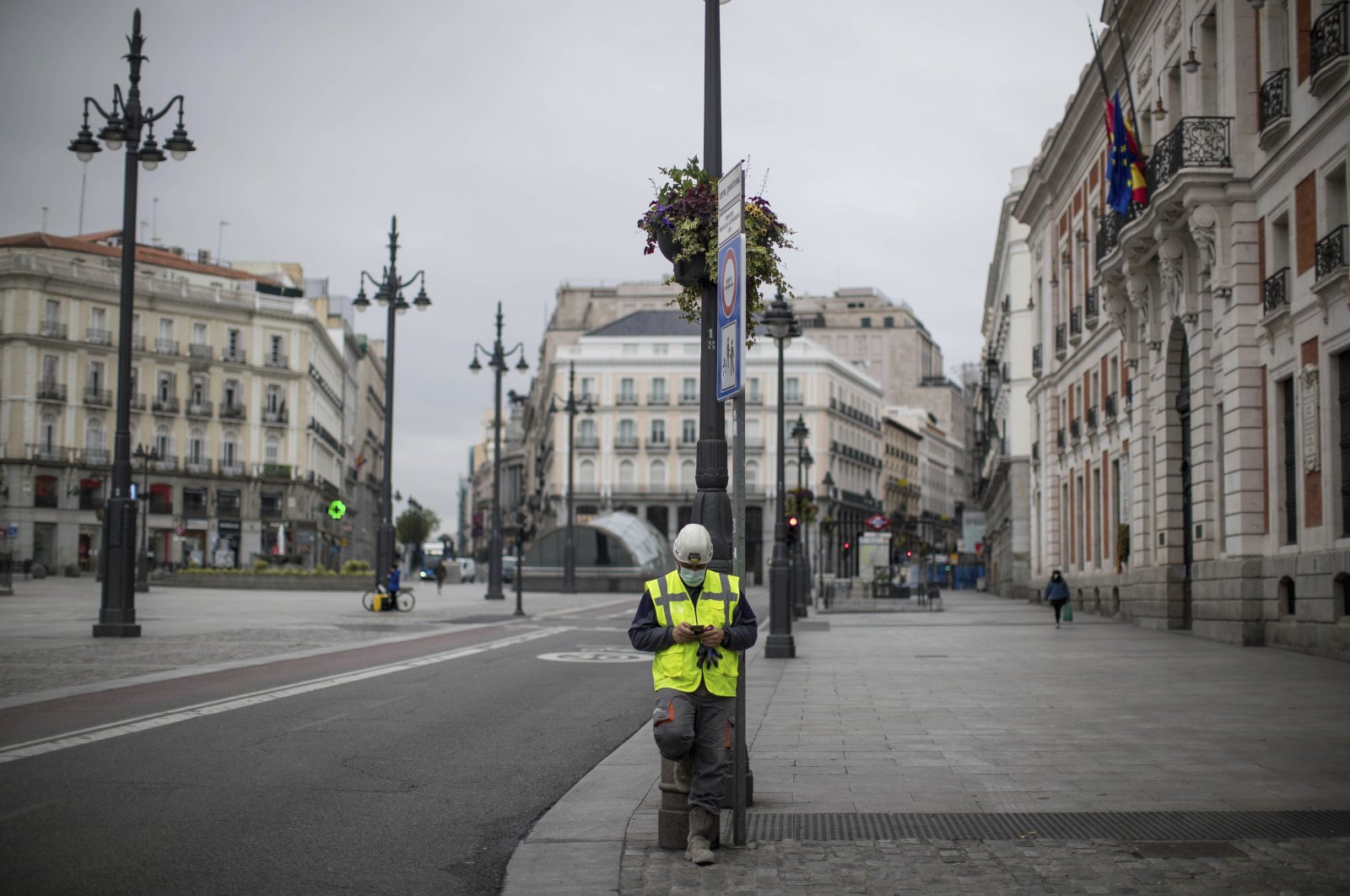 A worker checks his phone at the Sol square in Madrid, Spain, Tuesday, April 14, 2020.  (AP Photo)