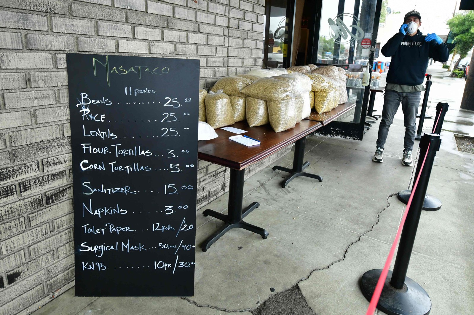 A menu lists items for sale outside David Fuertes's taco shop Masataco in Whittier, California, April 9, 2020. (AFP Photo)