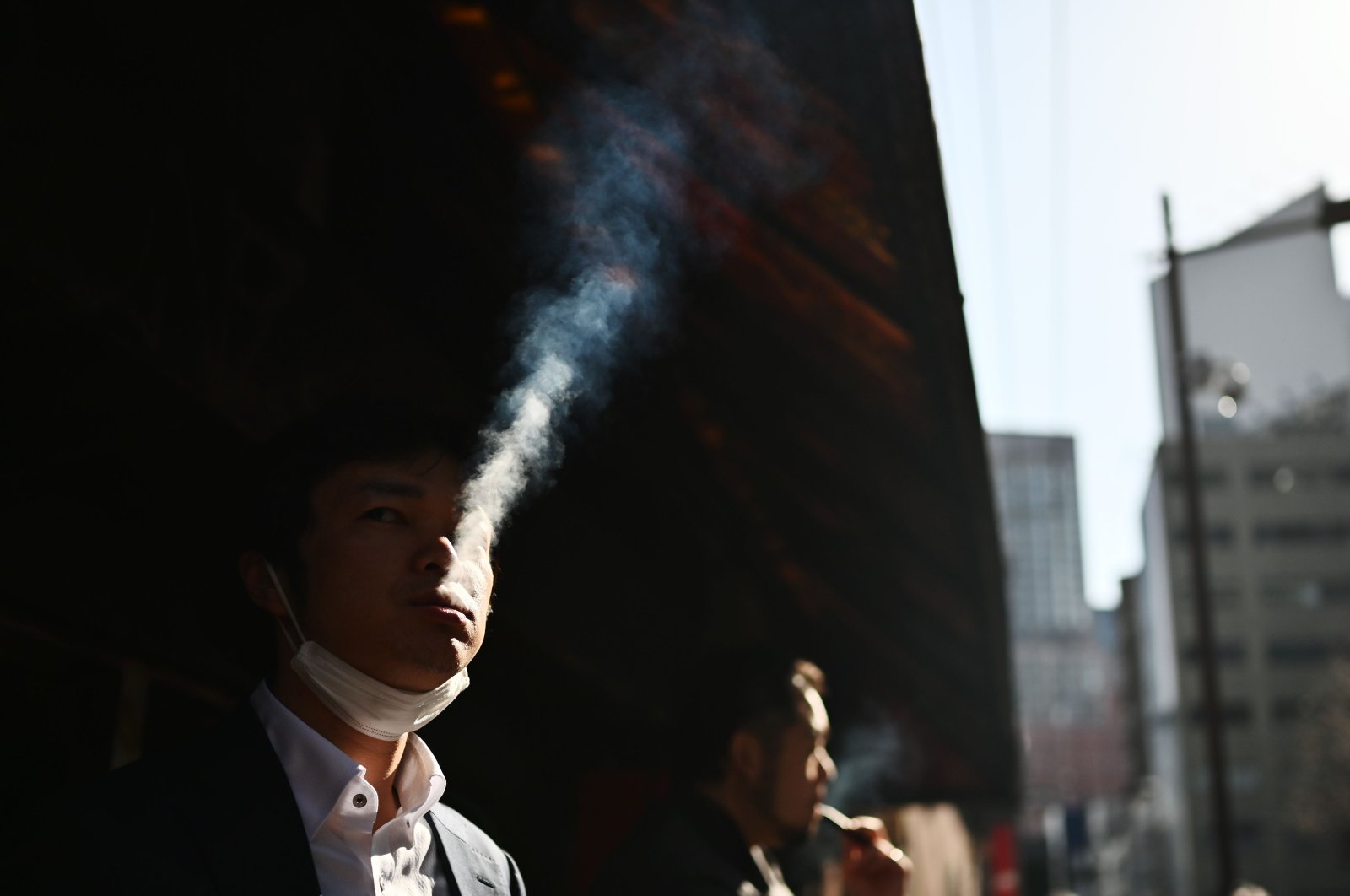 People smoke in a designated smoking area on a street in the Yurakucho area, Tokyo, Japan, March 26, 2020. (AFP Photo)
