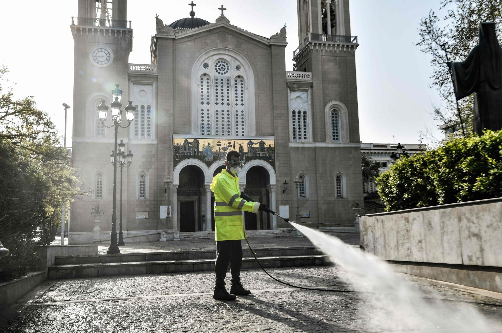 A municipal worker disinfects the forecourt outside Athens Metropolitan Church, Athens, Greece, April 15, 2020. (AFP Photo)