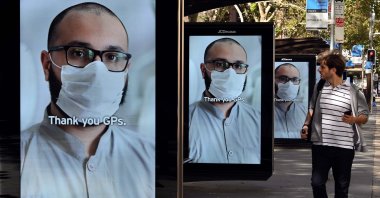 A man walks past bus stop advertising boards displaying thank you messages to health workers in response to the COVID-19 coronavirus outbreak, in Sydney on April 15, 2020. (AFP Photo)