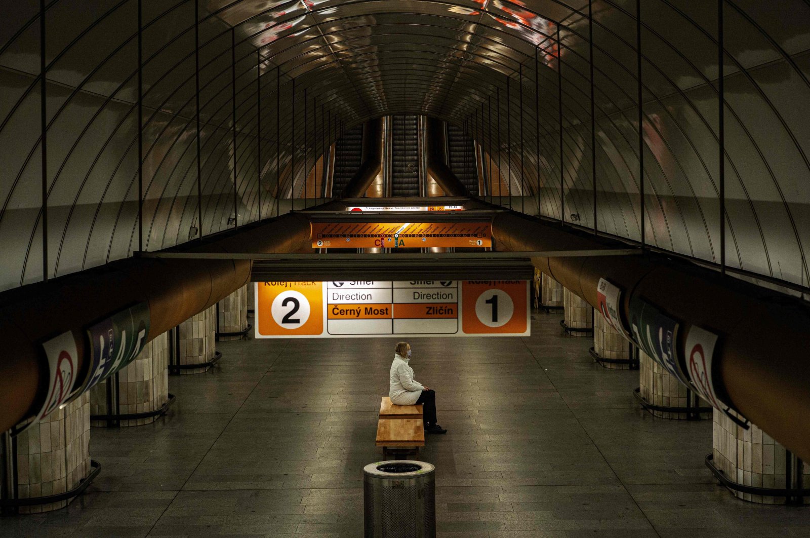 A woman wearing a face mask sits on a bench at an empty metro station in Prague, Czechia, amid restrictions due to the coronavirus pandemic, April 15, 2020. (AFP Photo)
