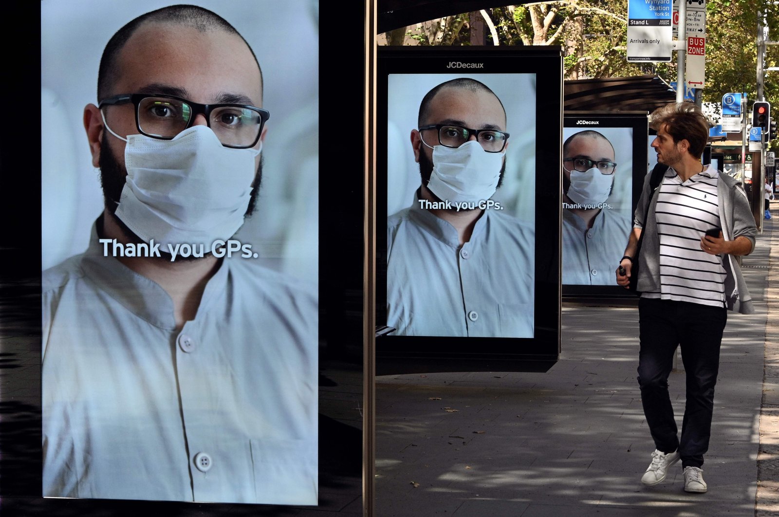 A man walks past bus stop advertising boards displaying thank you messages to health workers in response to the COVID-19 coronavirus outbreak, in Sydney on April 15, 2020. (AFP Photo)