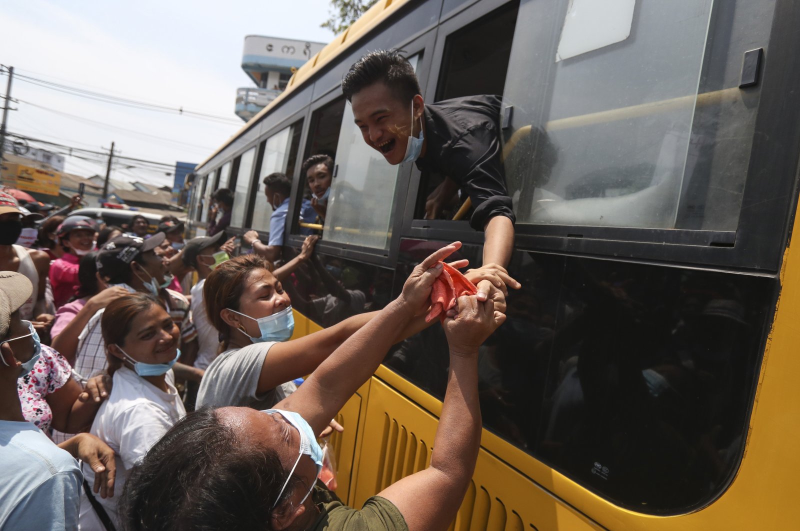 A prisoner reaches out from a bus to shake hands with family members after being released from the Insein prison during a presidential pardon in Yangon, Myanmar, Friday, April 17, 2020. (AP Photo)