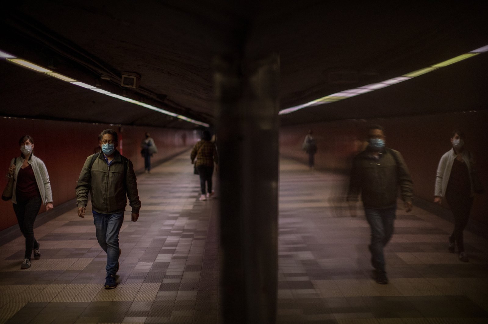 Passengers walk along a tunnel connecting platforms in a metro station in Barcelona, Spain, April 15, 2020. (AP Photo)