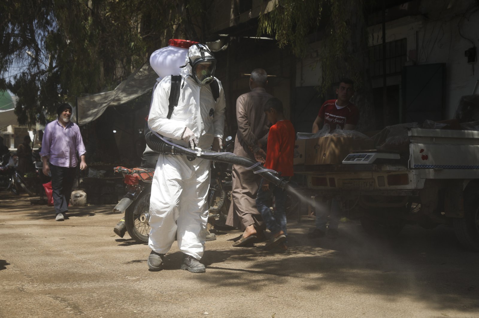 A member of a nongovernmental aid organization sprays disinfectant as a preventative measure against the coronavirus in the town of Armanaz, Idlib province, Syria, April 14, 2020. (AP Photo)