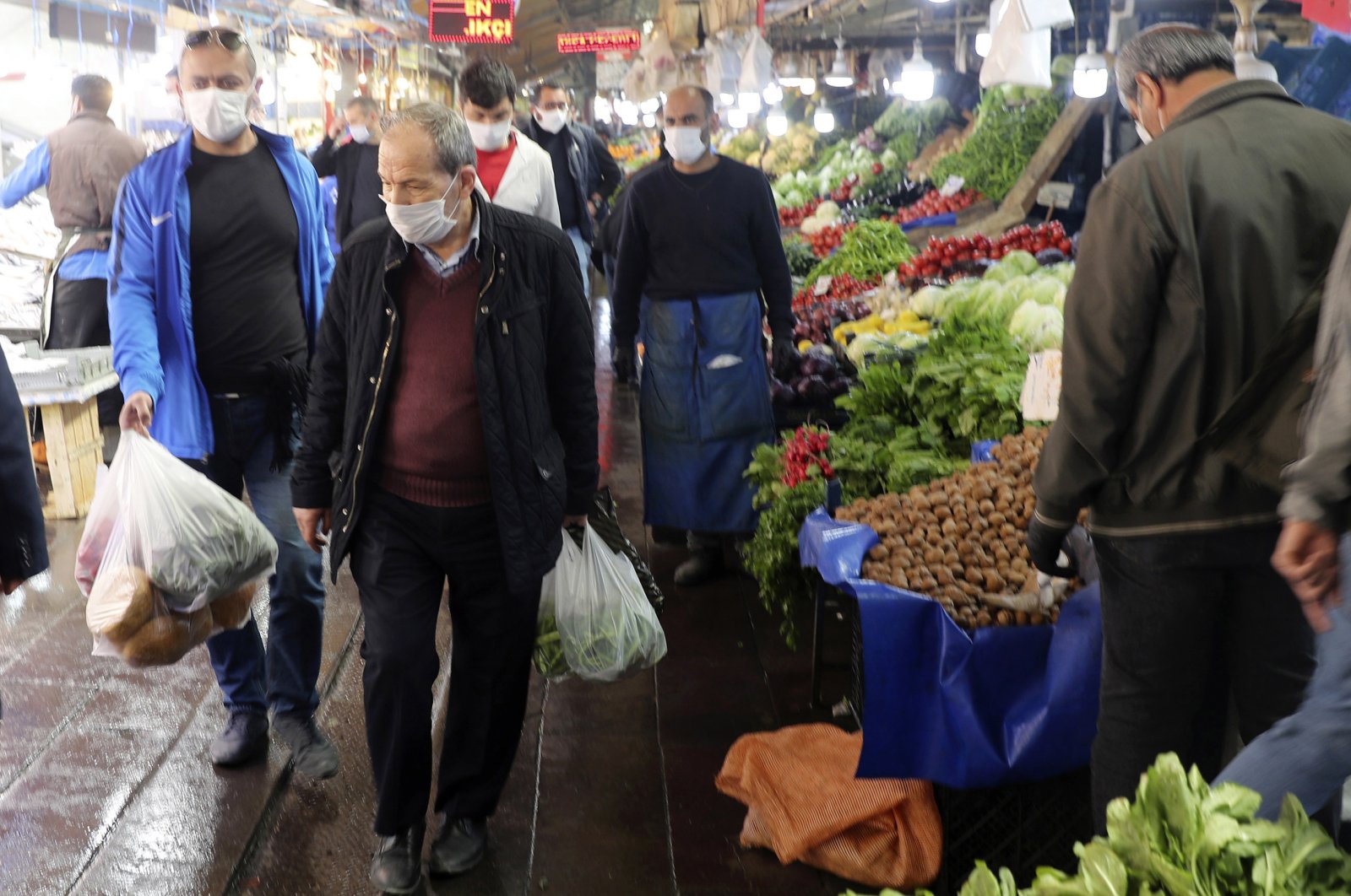People wearing face masks leave a food market just hours before the start of a two-day curfew declared by the government in an attempt to slow down the spread of coronavirus, in Ankara, Turkey, Friday, April 17, 2020. (AP Photo)