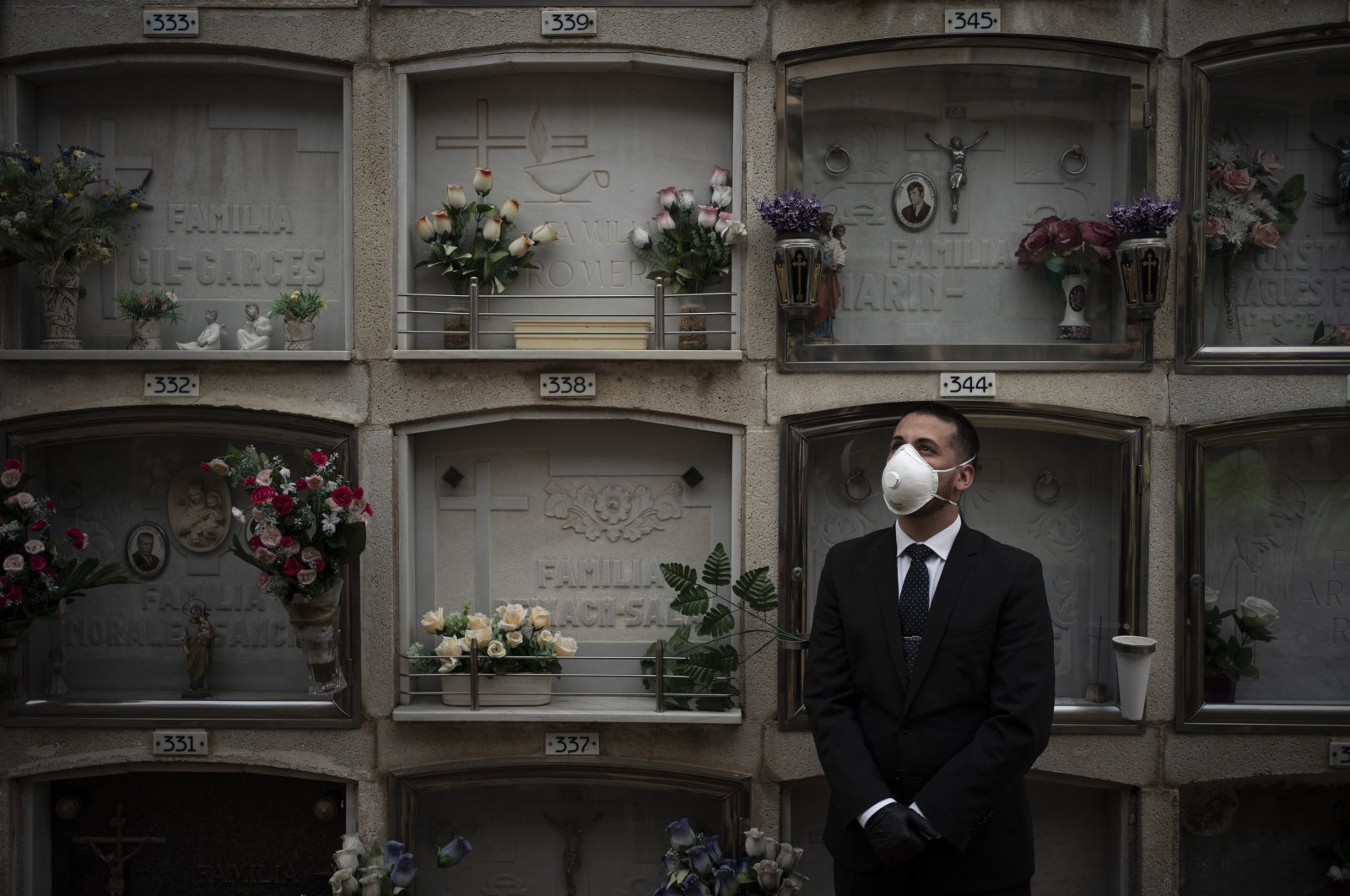 A funeral home worker wearing a face mask watches as the body of an unidentified person who died of unknown causes is placed into a niche at the Girona Cemetery in Girona, Spain, Friday, April 17, 2020. (AP Photo)