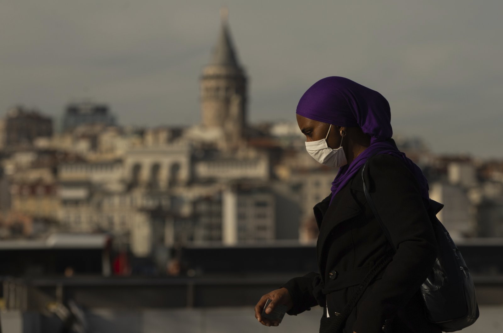 Backdroped by Istanbul's iconic Galata Tower a woman, wearing a mask as a preventive measure against the spread of coronavirus, walks in Istanbul, Friday, April 17, 2020. (AP Photo)