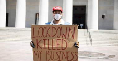 A protester holds a sign outside the Ohio Statehouse in Columbus, Ohio on April 18, 2020, to protest the stay-home order in effect until May 1. (AFP Photo)