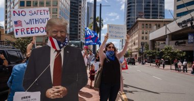 A Trump cutout with a US flag around its neck is seen next to protesters rallying in downtown San Diego against California's stay at home order to prevent the spread of the novel coronavirus, which causes COVID-19, on April 18, 2020. (AFP Photo)