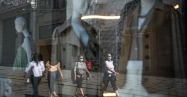 People wearing face masks due to coronavirus are reflected in a window shop of the Istiklal avenue before a weekend lockdown in Istanbul, Turkey, April 14, 2020.  (AFP Photo)